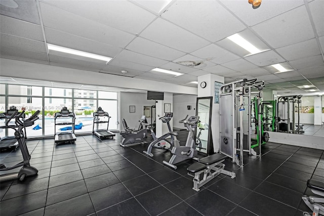 exercise room featuring a paneled ceiling and a wall of windows