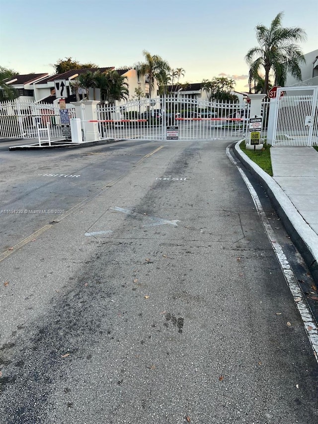 view of street with curbs, a gated entry, and a gate