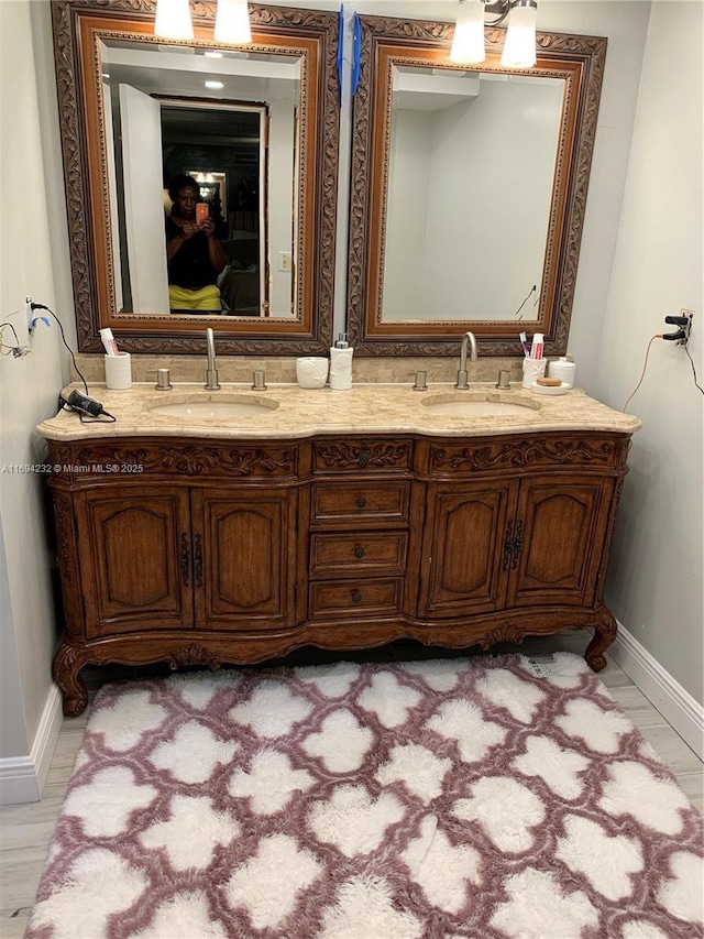 full bath with double vanity, baseboards, and a sink