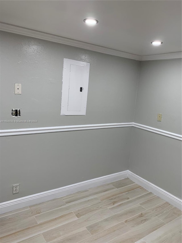 basement with electric panel and light hardwood / wood-style flooring