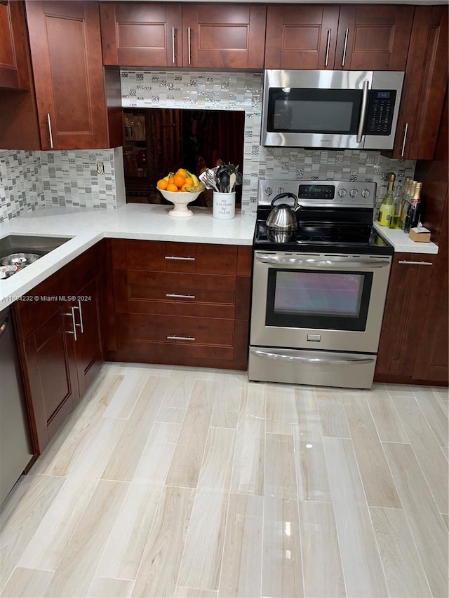 kitchen with light hardwood / wood-style floors, sink, appliances with stainless steel finishes, and tasteful backsplash