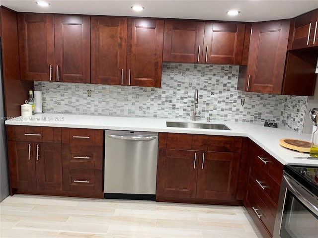 kitchen with light countertops, appliances with stainless steel finishes, a sink, and decorative backsplash