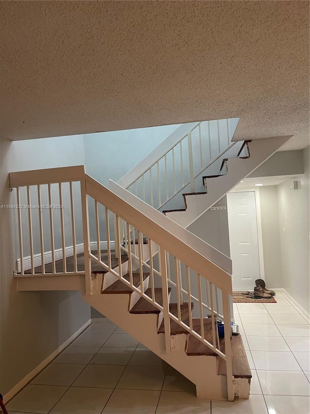 staircase with tile patterned flooring and a textured ceiling