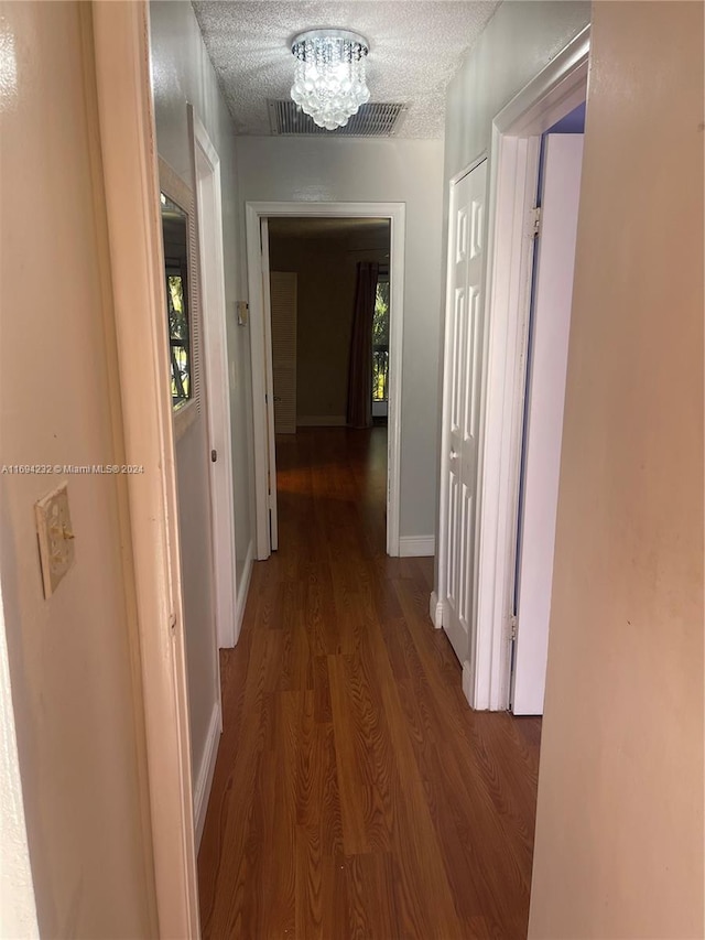 hall with a healthy amount of sunlight, a chandelier, a textured ceiling, and hardwood / wood-style flooring