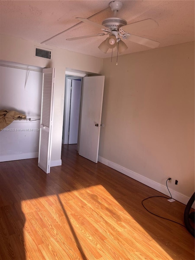 unfurnished bedroom featuring hardwood / wood-style flooring, ceiling fan, and a textured ceiling