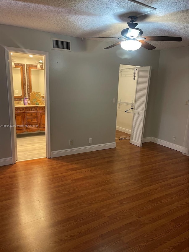 unfurnished bedroom with dark hardwood / wood-style flooring, ceiling fan, a closet, and a textured ceiling