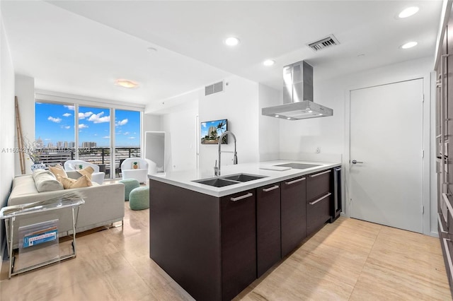 kitchen with kitchen peninsula, expansive windows, dark brown cabinetry, sink, and range hood