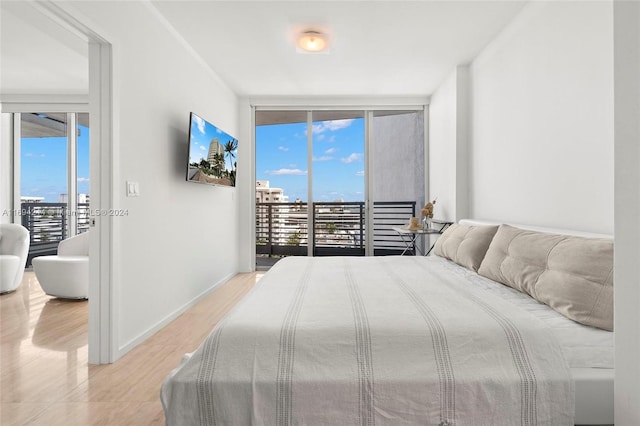 bedroom with access to exterior, a wall of windows, and light wood-type flooring