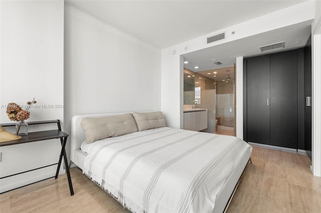 bedroom with ensuite bathroom and light hardwood / wood-style floors