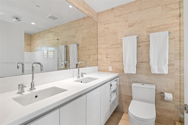 bathroom with vanity, toilet, and tile walls