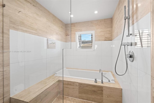 bathroom with tile walls and independent shower and bath