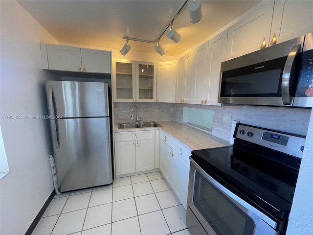 kitchen featuring appliances with stainless steel finishes, tasteful backsplash, sink, light tile patterned floors, and white cabinets