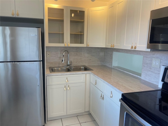 kitchen featuring white cabinetry, sink, backsplash, light tile patterned flooring, and appliances with stainless steel finishes