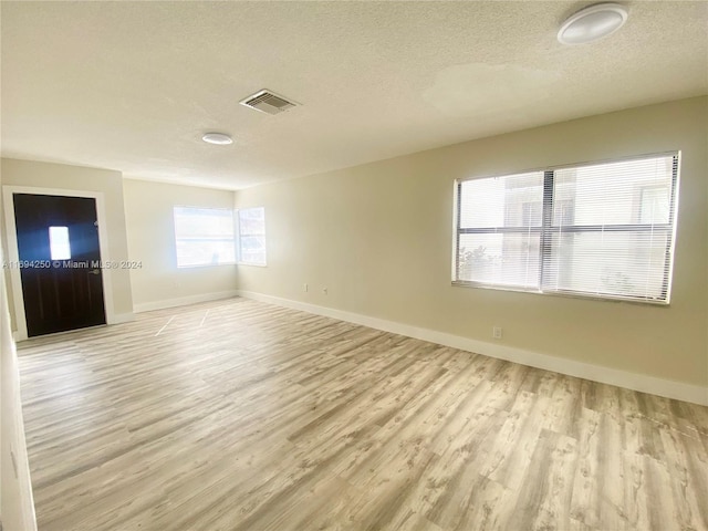 spare room with light hardwood / wood-style floors and a textured ceiling