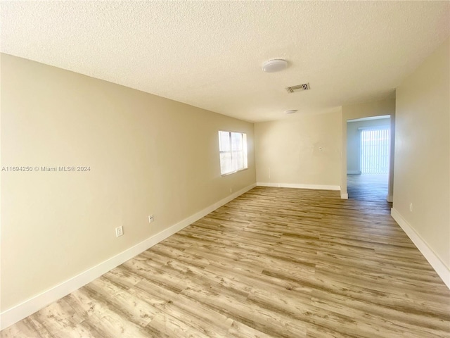 unfurnished room featuring light hardwood / wood-style flooring and a textured ceiling