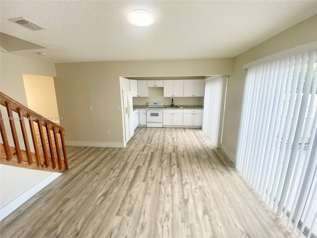 kitchen featuring a textured ceiling, sink, white range with electric cooktop, light hardwood / wood-style floors, and white cabinetry