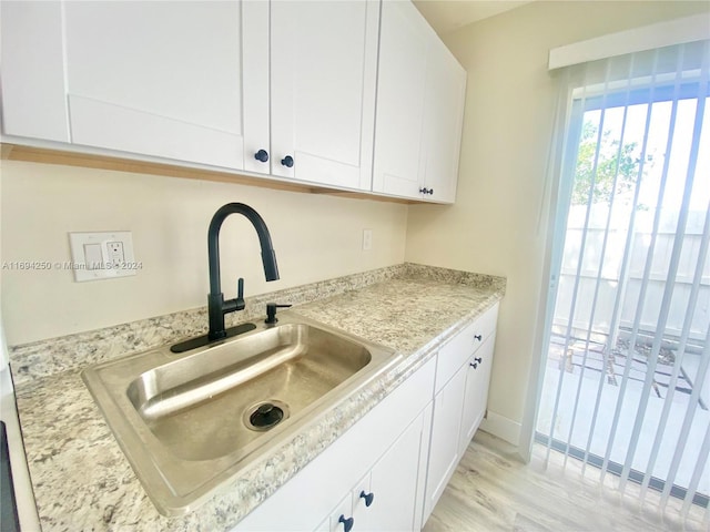 kitchen with light hardwood / wood-style floors, white cabinetry, and sink