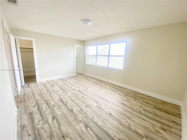 unfurnished bedroom with a textured ceiling, light hardwood / wood-style floors, and a closet