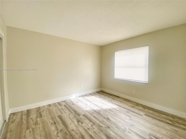 unfurnished room featuring light hardwood / wood-style floors and a textured ceiling