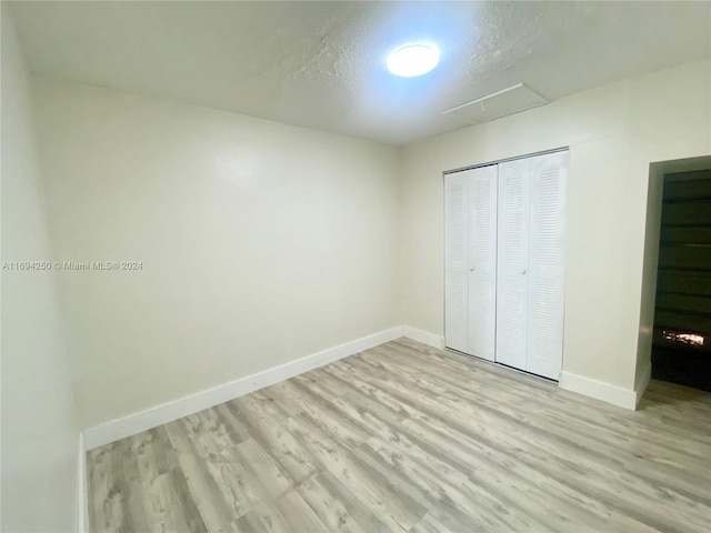 unfurnished bedroom with a textured ceiling, light hardwood / wood-style floors, and a closet