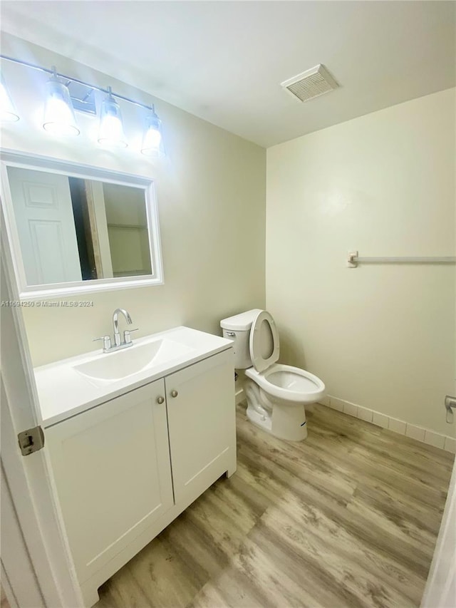 bathroom with vanity, toilet, and wood-type flooring