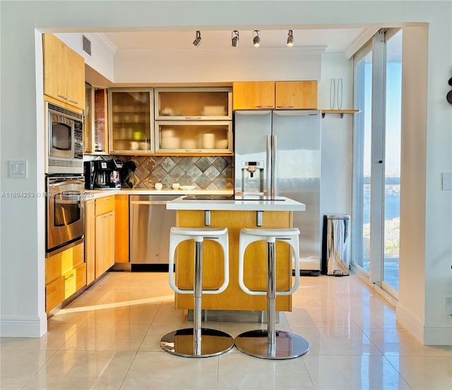 kitchen featuring a breakfast bar area, light tile patterned flooring, tasteful backsplash, and appliances with stainless steel finishes