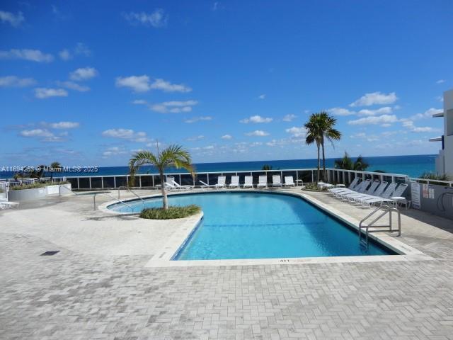 view of pool featuring a patio and a water view