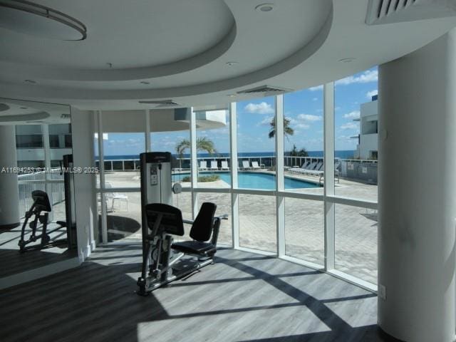 gym with a wall of windows and a raised ceiling