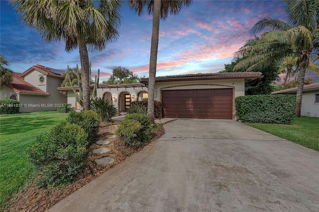 mediterranean / spanish-style home featuring a lawn and a garage