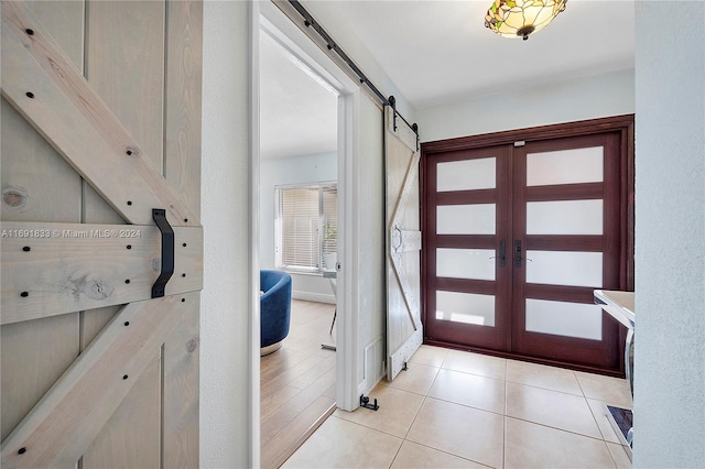 entryway with a barn door, light hardwood / wood-style floors, and french doors