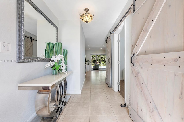 corridor with a barn door and light tile patterned floors