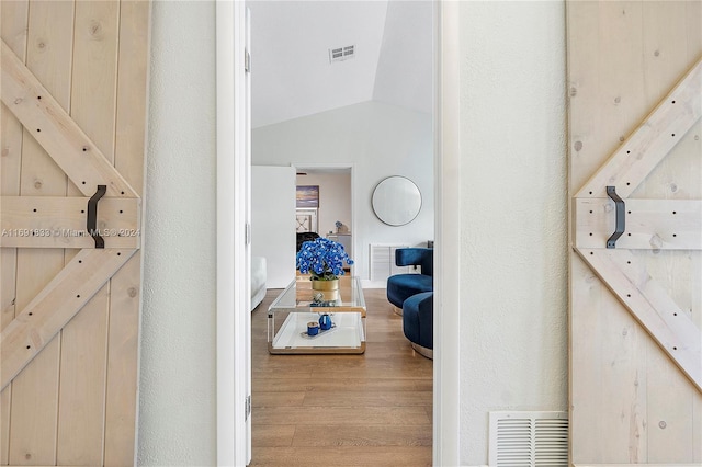 corridor with light hardwood / wood-style flooring and lofted ceiling