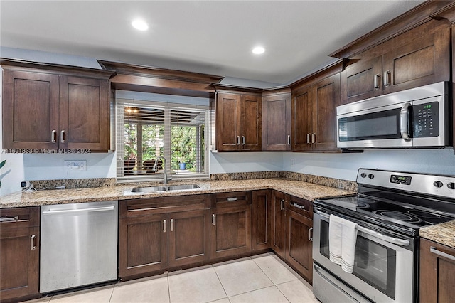 kitchen with dark brown cabinetry, light stone countertops, sink, light tile patterned floors, and appliances with stainless steel finishes