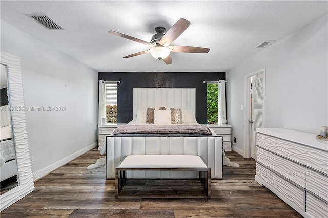 bedroom with ceiling fan, dark hardwood / wood-style flooring, and a textured ceiling