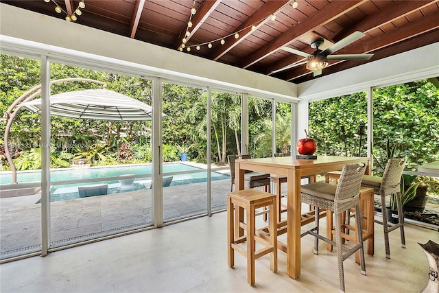 sunroom featuring beam ceiling, ceiling fan, a healthy amount of sunlight, and wood ceiling