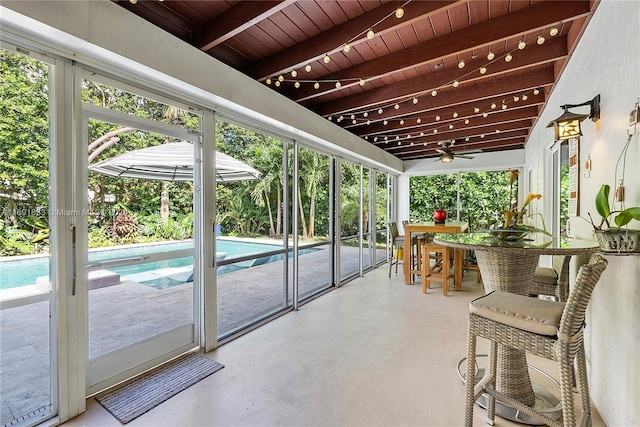 sunroom / solarium with beam ceiling, ceiling fan, and wooden ceiling