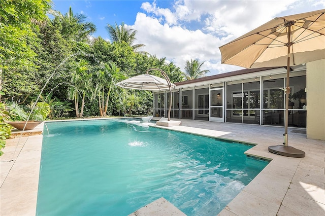 view of pool with pool water feature, a patio area, and a sunroom