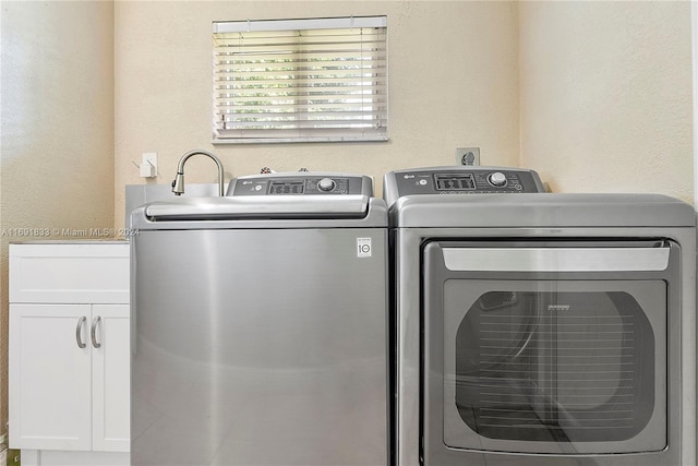 laundry area featuring washing machine and clothes dryer and cabinets