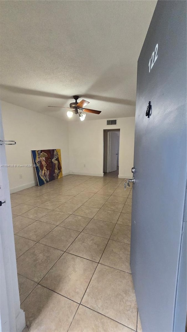 spare room with ceiling fan, light tile patterned flooring, and a textured ceiling