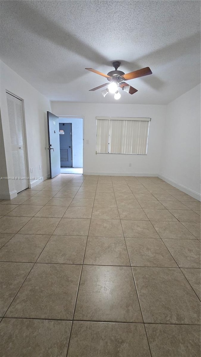 tiled spare room with a textured ceiling and ceiling fan