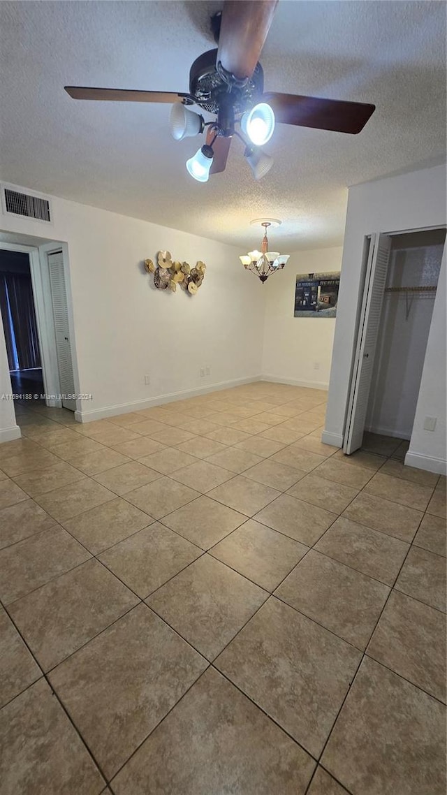 spare room featuring a textured ceiling, tile patterned floors, and ceiling fan