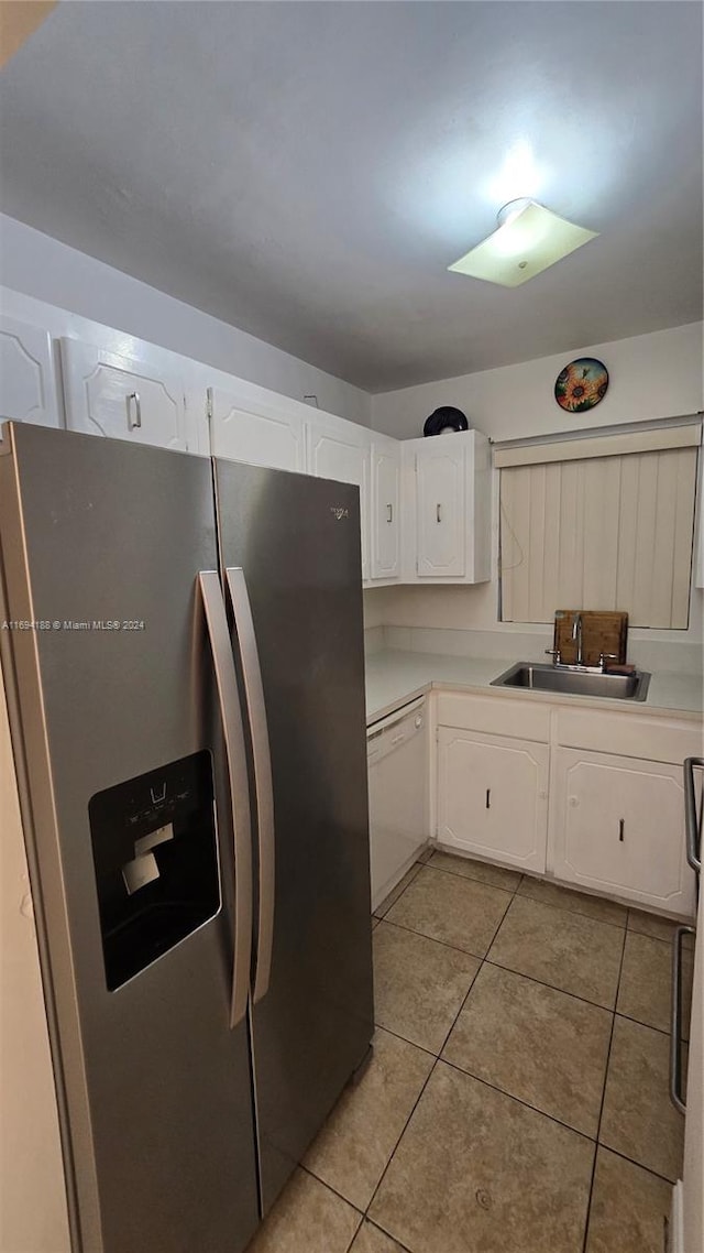 kitchen with white cabinetry, dishwasher, sink, stainless steel fridge, and light tile patterned floors