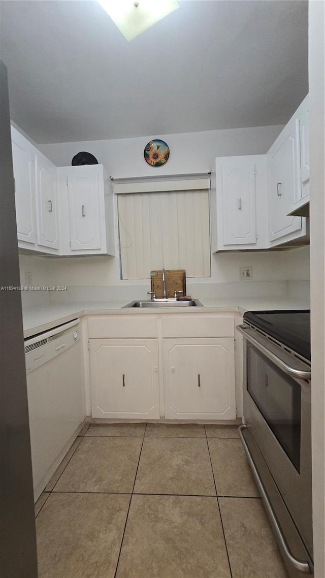 kitchen with white dishwasher, white cabinets, sink, stainless steel stove, and light tile patterned flooring