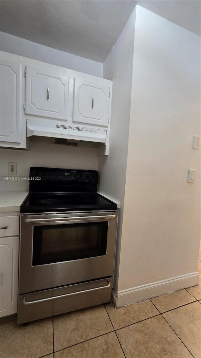 kitchen featuring light tile patterned floors, electric range, and white cabinetry