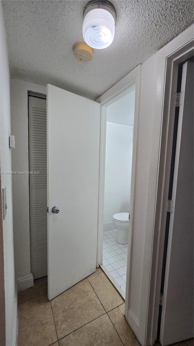 corridor with light tile patterned floors and a textured ceiling