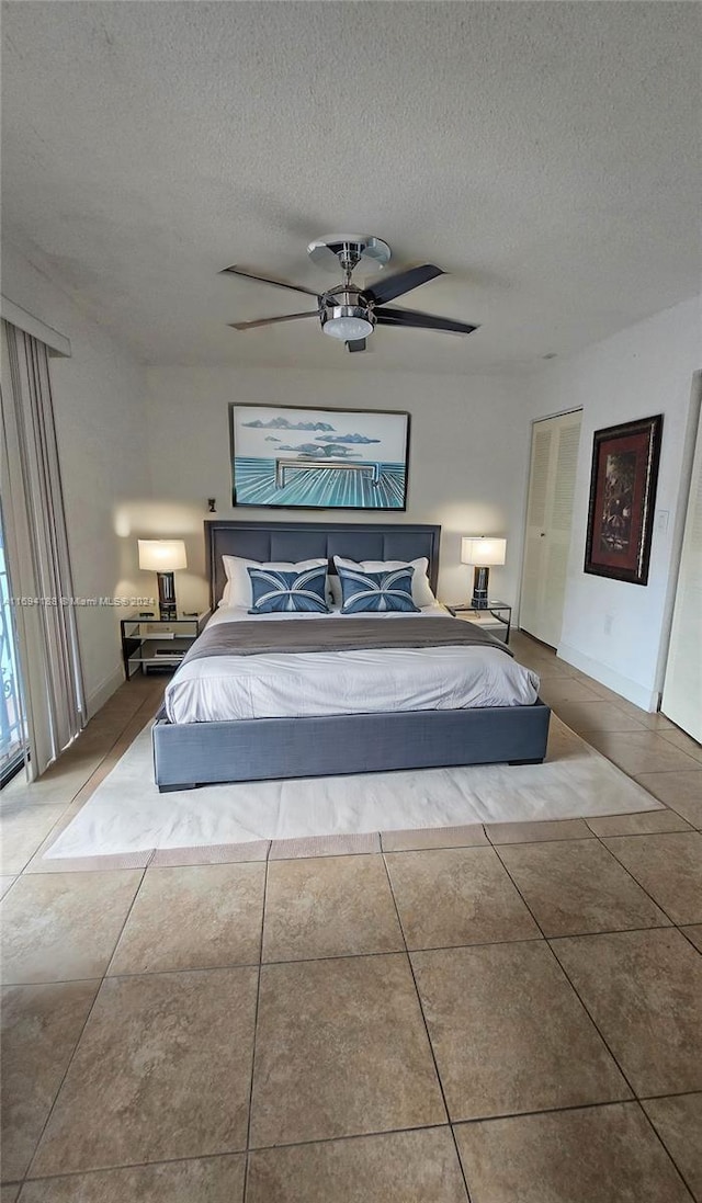 unfurnished bedroom with ceiling fan, tile patterned flooring, and a textured ceiling