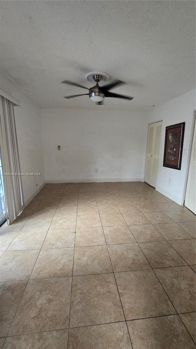 tiled empty room featuring a textured ceiling and ceiling fan