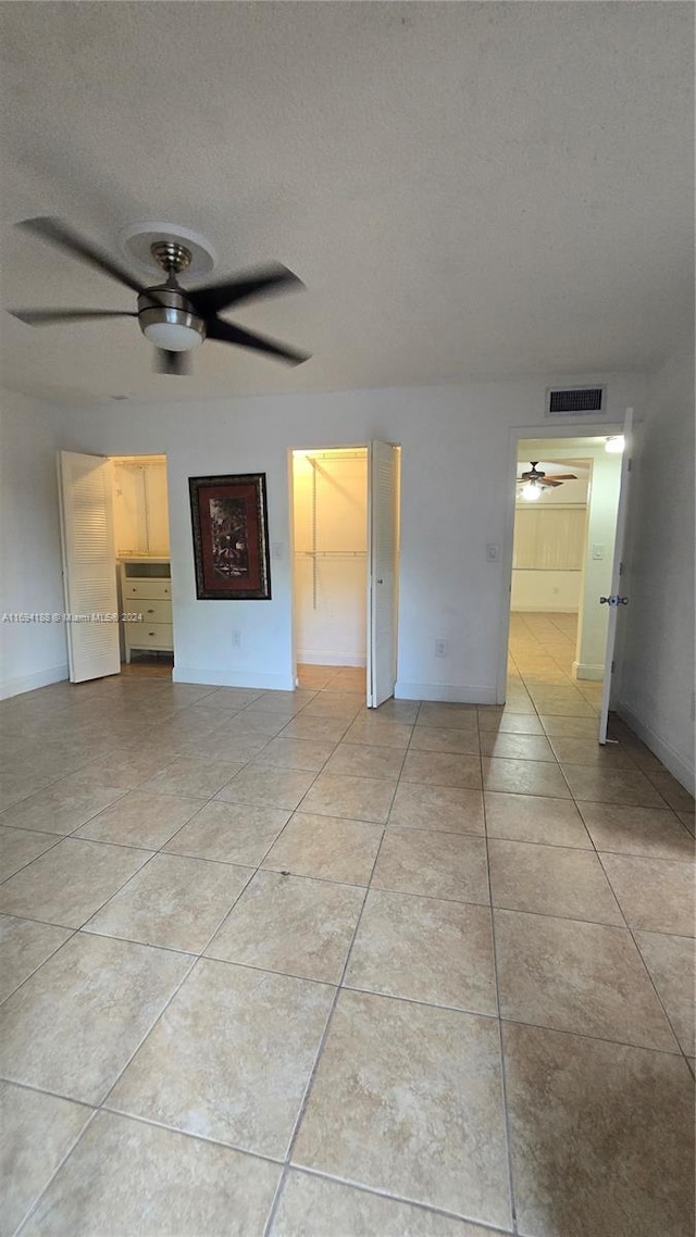 tiled empty room with a textured ceiling and ceiling fan