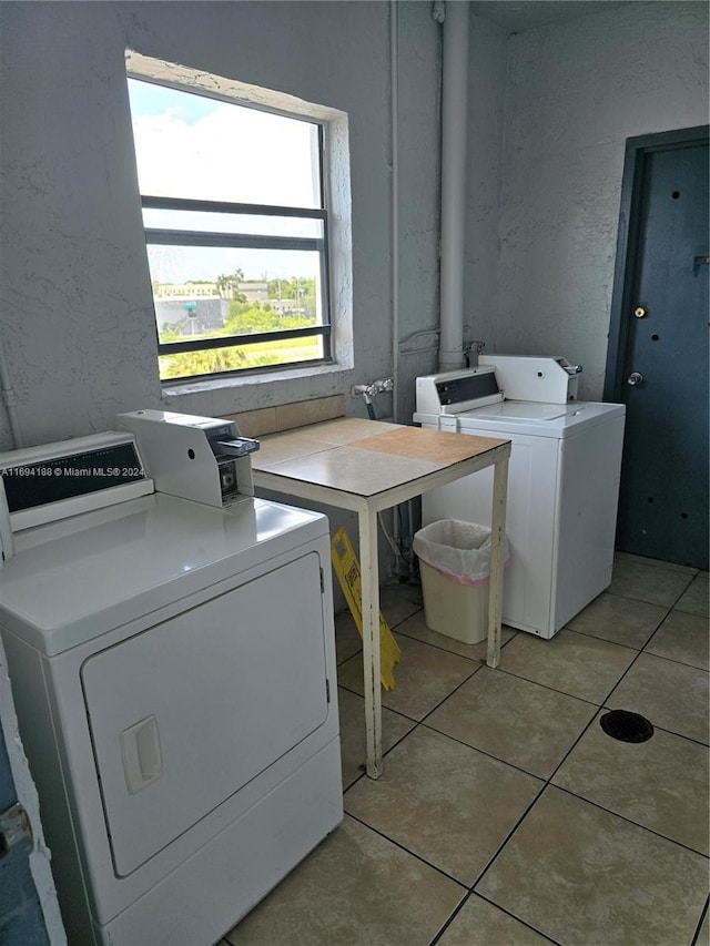 clothes washing area with separate washer and dryer and light tile patterned flooring