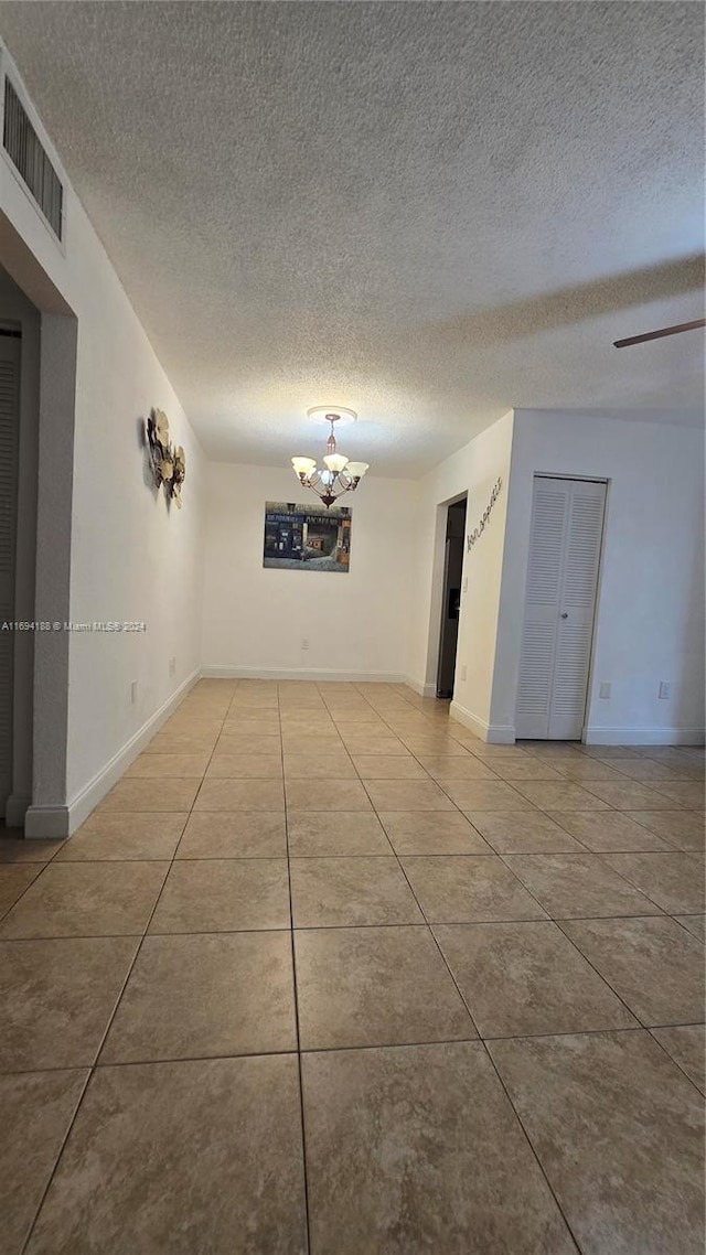 tiled empty room featuring a textured ceiling